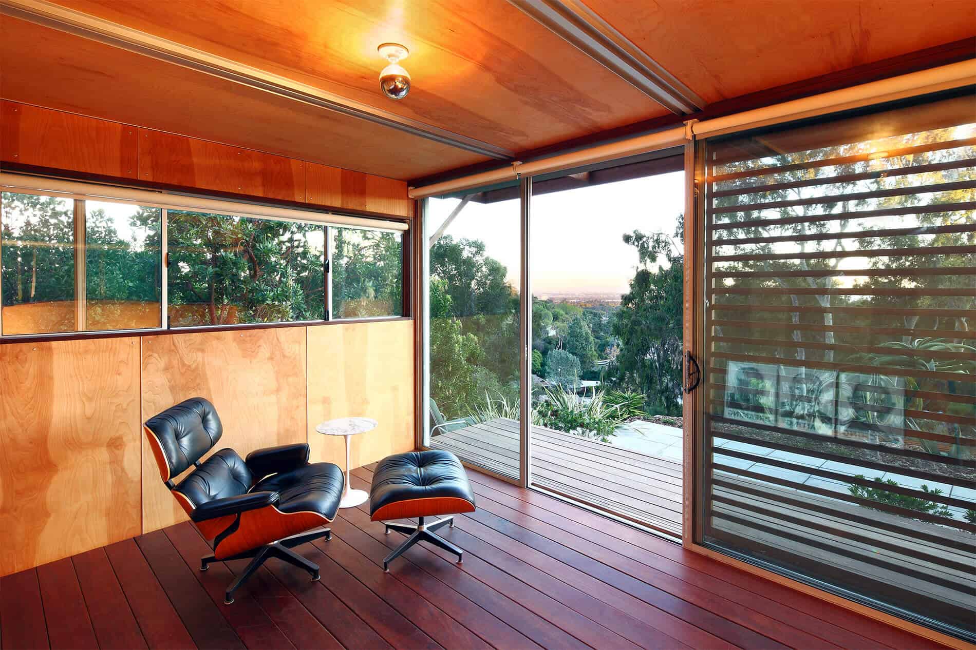 室内装饰着丰富的红色木地板，浅色的天然木墙和天花板，室外的全玻璃视野与遮阳板。