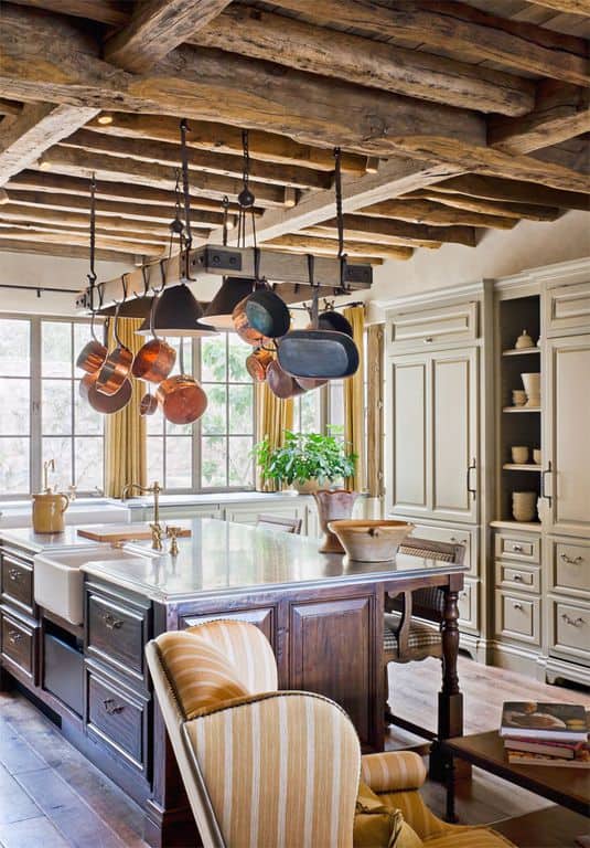 这个明亮的厨房有优雅和优雅的橱柜和抽屉在其深色的木制厨房和浅灰色的橱柜在墙上。这些与木质天花板形成了质朴的对比，木质天花板有粗糙和有纹理的裸露木梁。