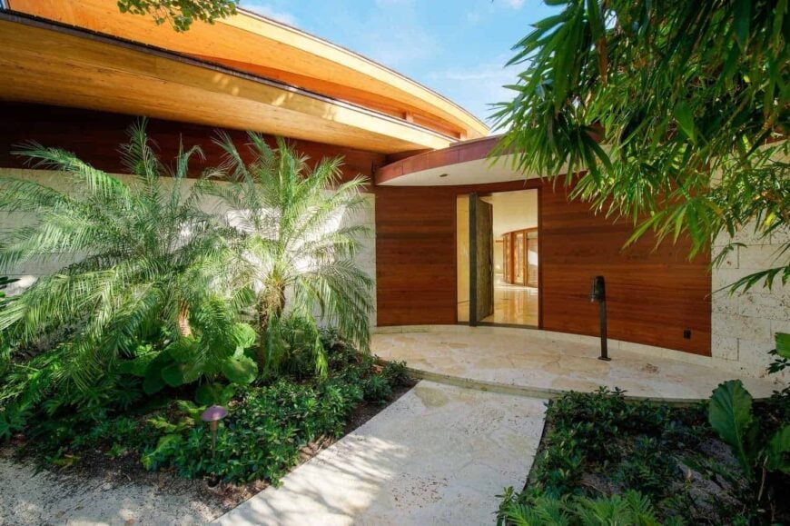 石板走道和配套的平台通往以非常规方式打开的深色木质前门。它与热带植物相辅相成，为房子增添了美好的色彩。