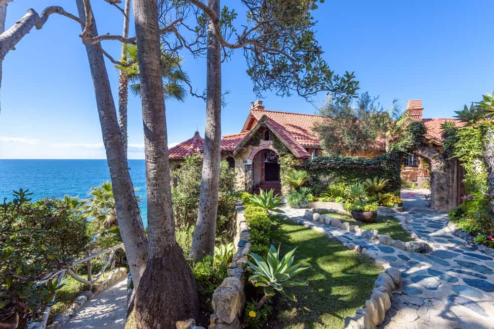这座美丽的住宅坐落在悬崖上，俯瞰大海，景色优美，增添了地中海风格房屋的美丽，屋顶涂有灰泥。图片来自Toptenrealestatedeals.com。