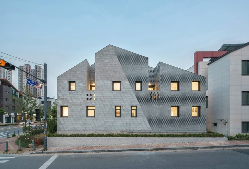 这是房子北侧的夜景,展示了用于外部的两种类型的混凝土砖,并辅以窗户的温暖辉光。
