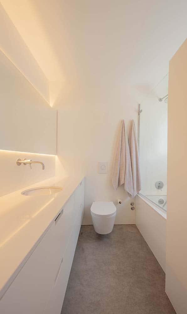 这是主浴室，墙壁采用了一致的白色调，现代的浮动梳妆台，卫生间和浴缸在梳妆台的对面。