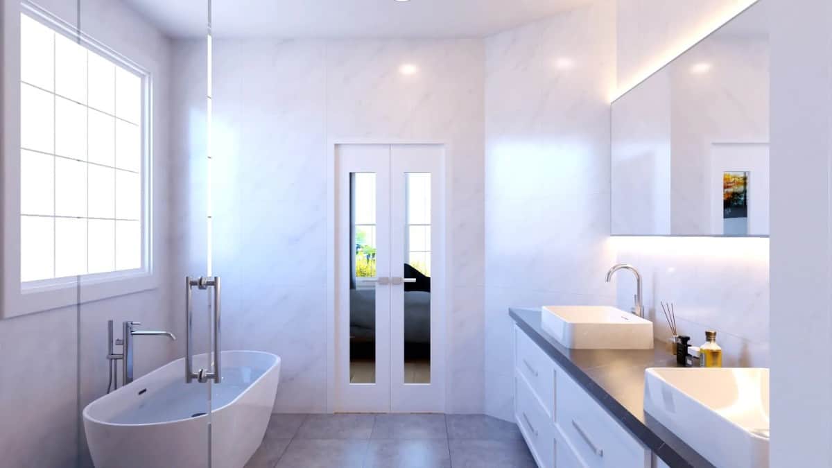 一扇法式门通向主浴室。它有一个独立的浴缸和一个白色的梳妆台，上面有两个水槽和一面无框镜子。