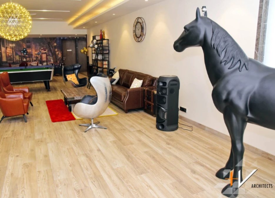 一个游戏室的内部镜头，里面有一个小台球桌和一个黑马雕塑。