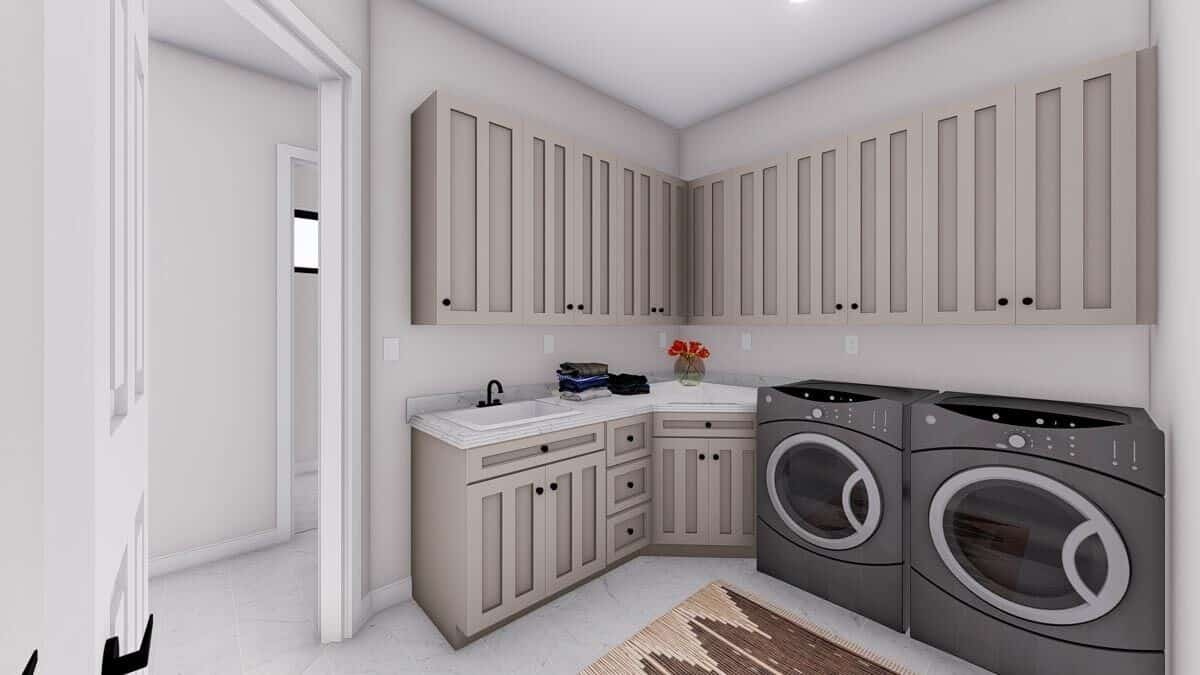 洗衣房有一台前置洗衣机和烘干机，一个多功能水槽和灰褐色的橱柜。
