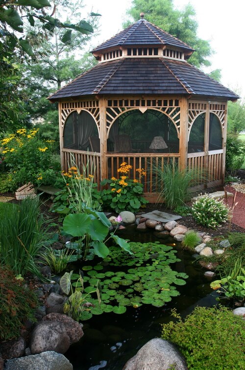这个木质凉亭的边缘很宽，坐落在一个水族花园的边缘。