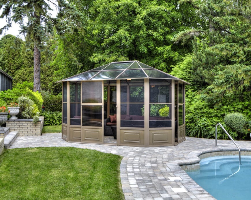 玻璃屋顶使封闭的凉亭成为后院完美的独立日光浴室。这里，它在一个可爱的游泳池旁边。