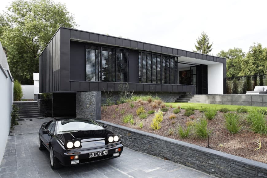 一栋黑色的现代住宅，有一条漂亮的车道直通车库。