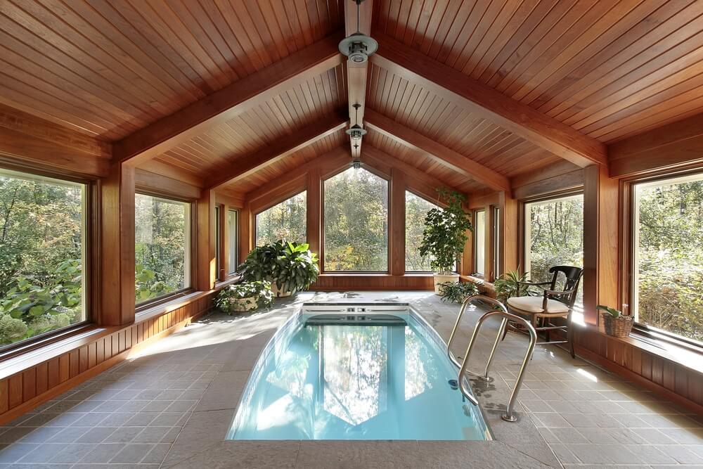 全木制和玻璃的室内泳池侧翼。天花板和部分墙壁是木质的。游泳池的规模相当小。窗户环绕着空间，带来了充足的自然光线。