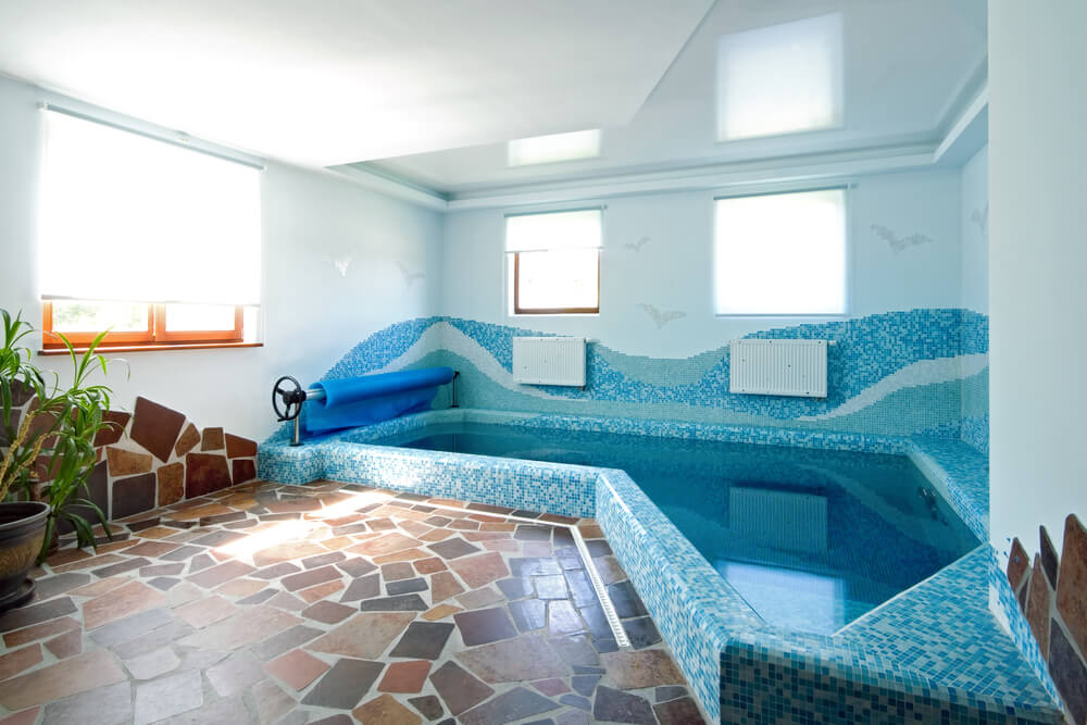 小型室内游泳池与蓝色瓷砖图案和石头工作的小型内部泳池甲板。