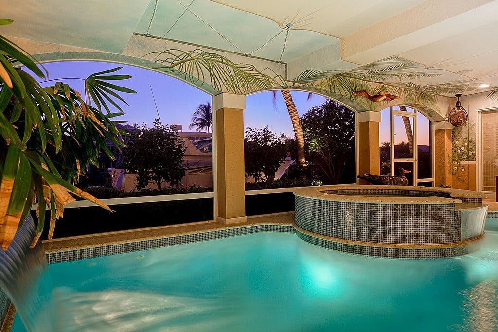 带热水浴缸的游泳池露台和通往后院的拱形门廊。