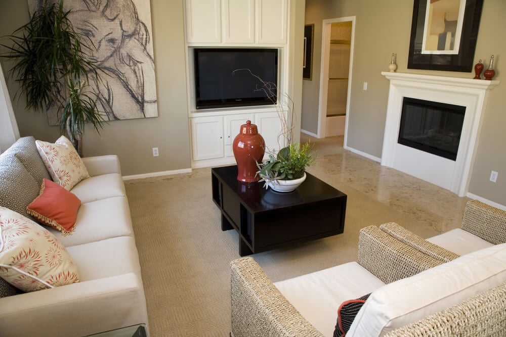 现代的客厅设计，有两把柳条扶手椅，一个白色沙发，平板电视放置在定制的内置白色橱柜中，还有一个带白色小壁炉的小型燃气壁炉。
