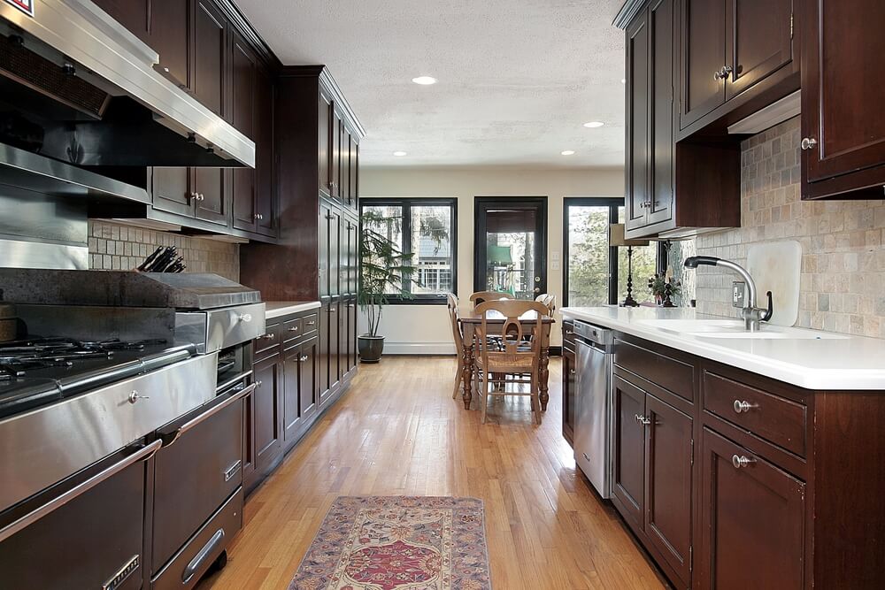 狭窄的烹饪区通往宽敞的餐厅，厨房配有熟悉的深色木橱柜和自然浅色的硬木地板。
