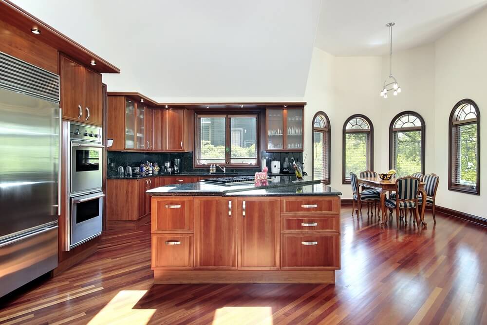 这个厨房拥有一个高耸的天花板和圆形风格的用餐区，在每个其他表面上都有丰富的木材色调。