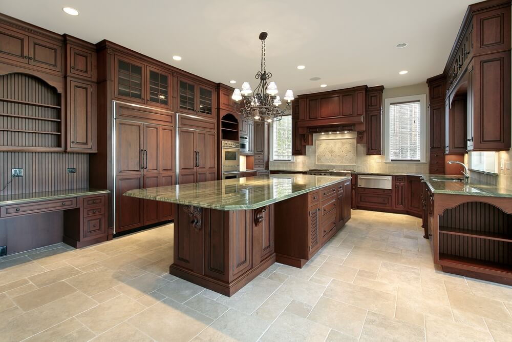 深色丰富的木材色调在这个以瓷砖地板和绿色花岗岩台面为特色的明亮厨房中脱颖而出。