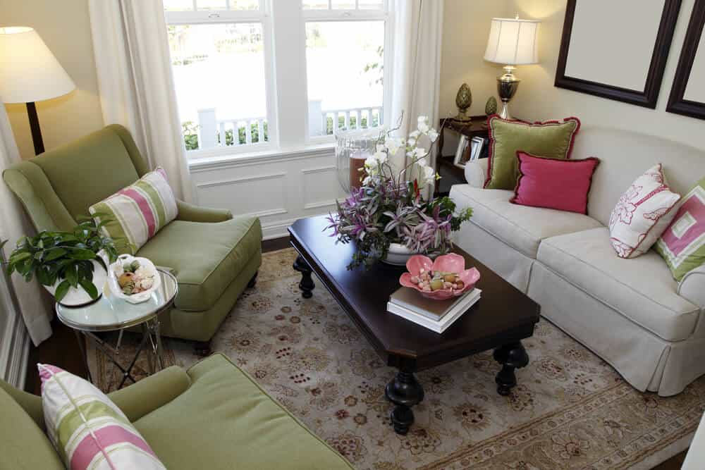 彩色设计的小客厅空间，绿色扶手椅和米白色沙发。整个房间的枕头都是绿色、米白色和粉红色，为空间增添了色彩。