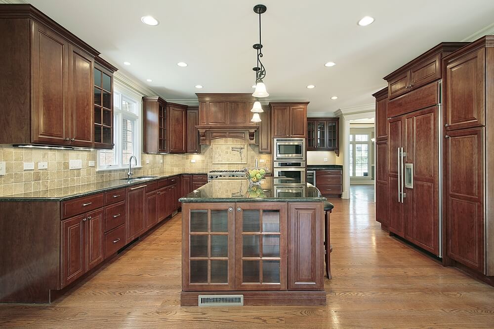 在这间厨房里，浅色硬木地板和深色木橱柜相互映衬，设有浅色瓷砖后挡板和隐藏的照明。