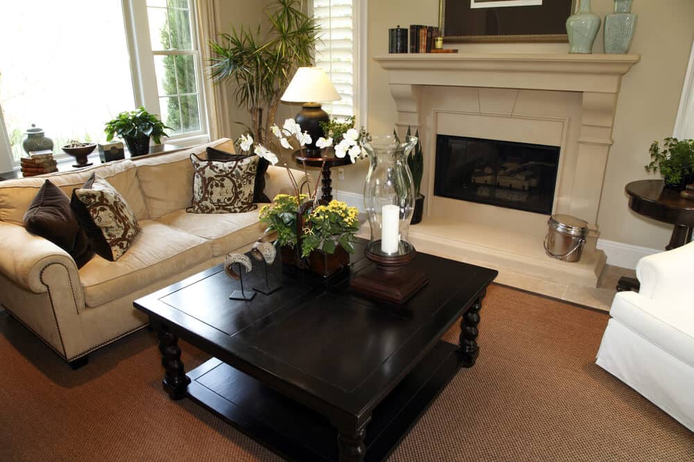 小客厅，红棕色地毯，浅米色沙发，深色木方形咖啡桌和全白色扶手椅。
