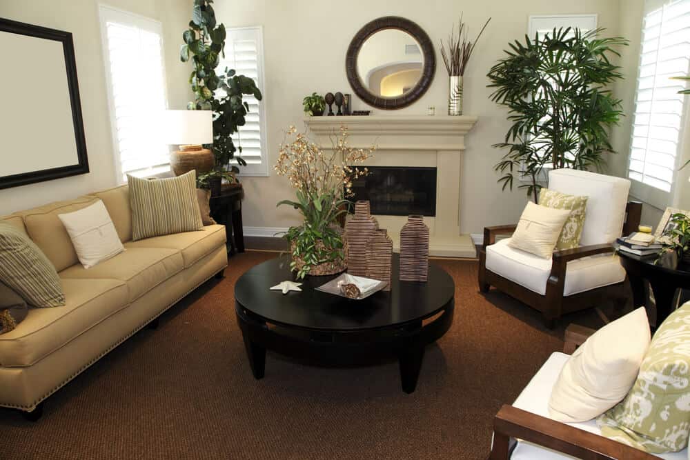 舒适的客厅，木框架扶手椅对着圆形暗木咖啡桌和浅棕色沙发。