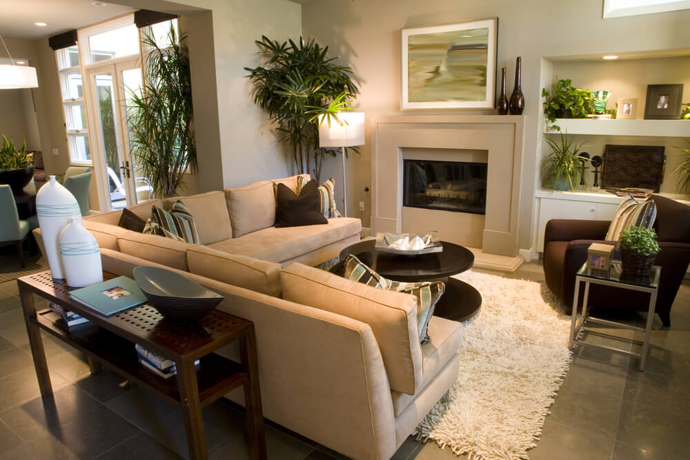在这个非常小的客厅空间里，l形沙发、圆形咖啡桌和一张大棕色扶手椅都放在灰白色的粗毛地毯上，非常注重细节。