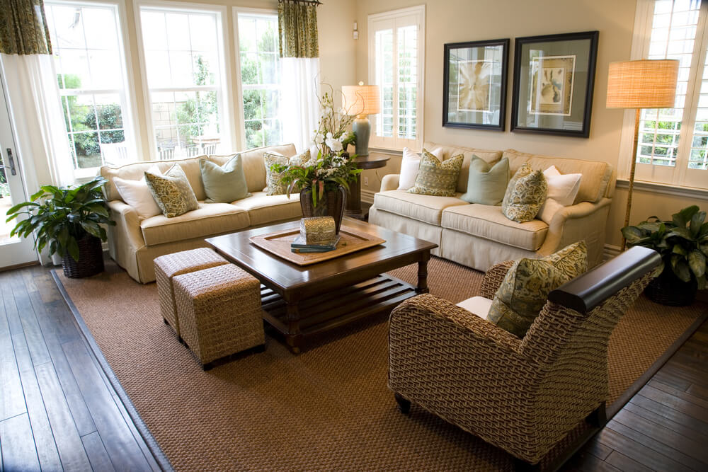 现代的客厅设计，两个配套的米白色沙发，白色和柔软的绿色枕头。一把柳条扶手椅。方形咖啡桌，辅以两个小柳条脚垫。