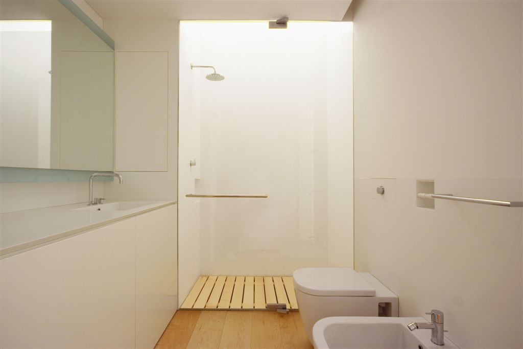 第二个浴室展示全白色设计，天然硬木地板，极简主义的角度，和玻璃淋浴。