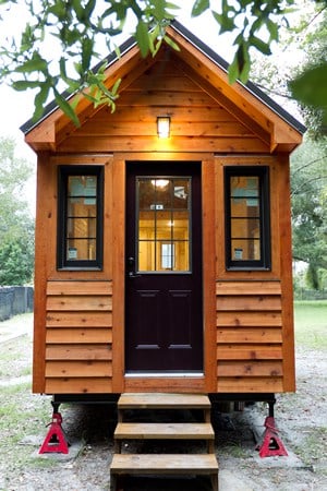这是一个相同的微型住宅，坐落在一个更传统的院子里。黑色的门窗与外部形成对比。