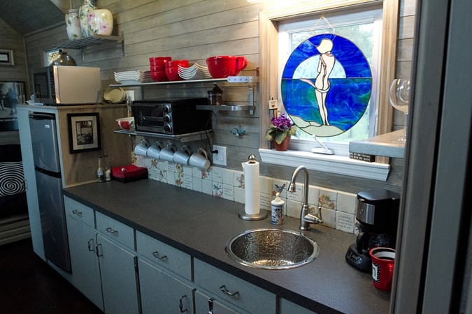 全功能厨房持有宽度的黑色台面与水槽下的玻璃窗盖，左边有电器。