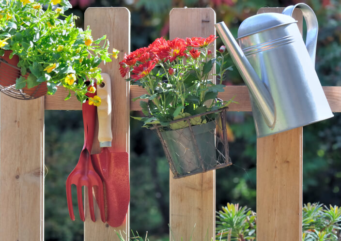 花园栅栏的设计特点是稀疏、间距大的柱子，带有用于园艺工具的挂钩。