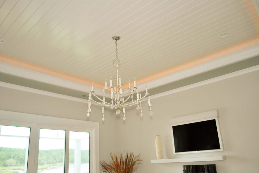 卧室的天花板设有环绕式嵌入式照明，而壁挂式电视可以在极简主义的吊灯之外看到。