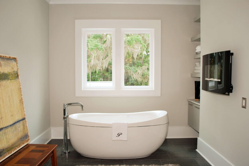 独立底座浴缸，深色瓷砖地板，浴室内设有小型壁挂式壁炉。