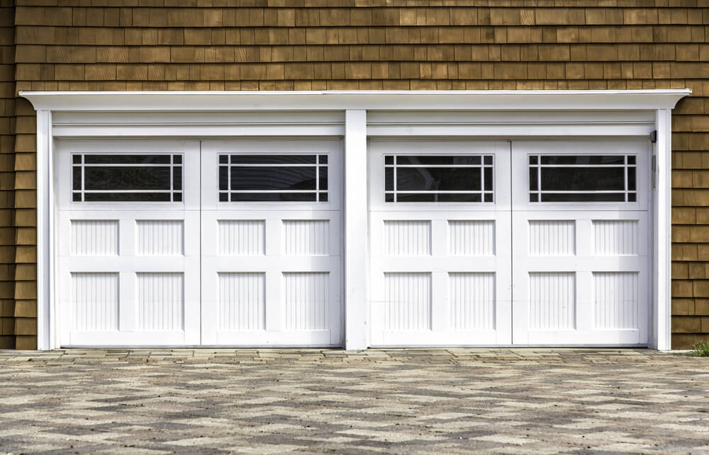 天然木瓦壁板围绕着两个车库，采用白色漆木，具有大的上面板窗户设计。