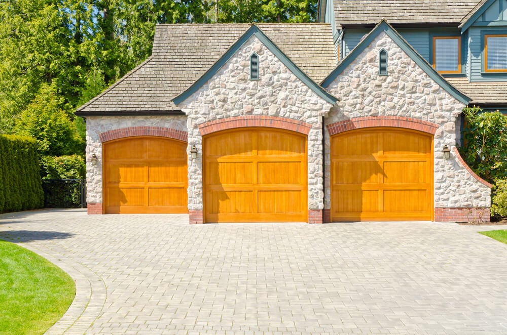 前三个车库的特点是交错设计，两个轻天然木门在前面，第三个凹在左边。红砖拱门的门框在石头立面下。