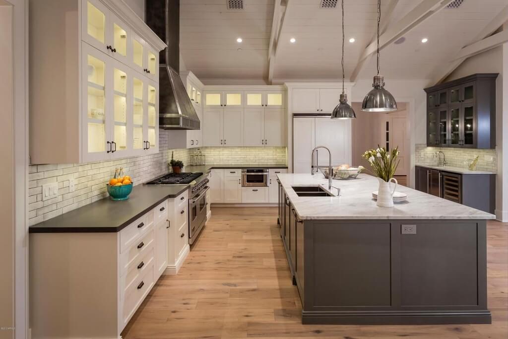 大型现代厨房设计，白色和灰色配色方案。巨大的中心空间包括一个巨大的岛，提供了柜台空间的最大份额。冰冷的灰色色调被温暖的天然木地板抵消了。