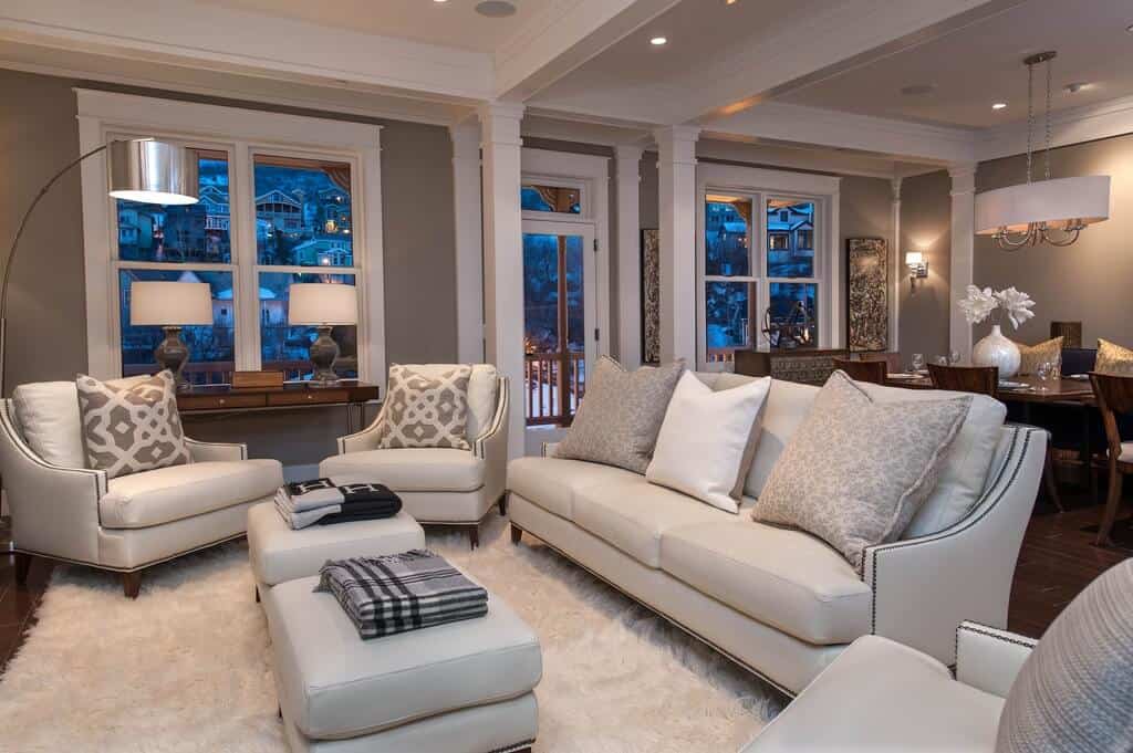 深色硬木地板上的白色蓬松地毯支撑着这套白色皮革家具，包括带靠垫的双矩形沙发。