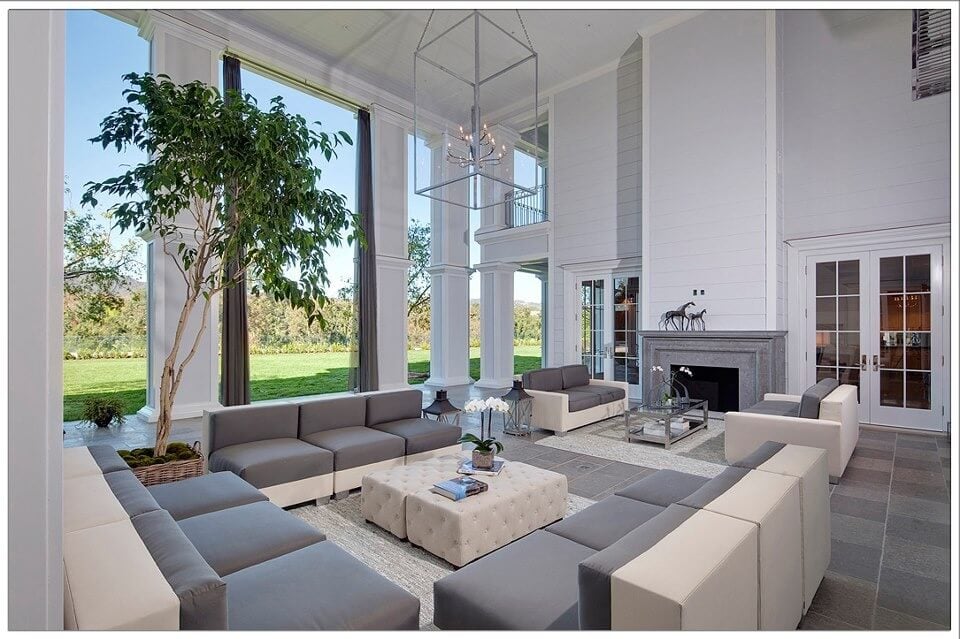 巨大的灰色和白色调的两层客厅，以双色组合沙发为特色，围绕米色纽扣簇绒皮革长椅沙发。