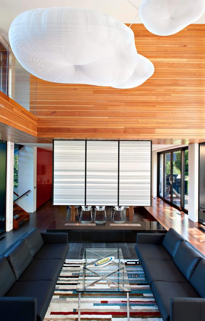 可以直接看到座位区:低挂皮革沙发对面是玻璃和抛光金属咖啡桌，悬挂的白色分隔墙分隔了用餐空间。