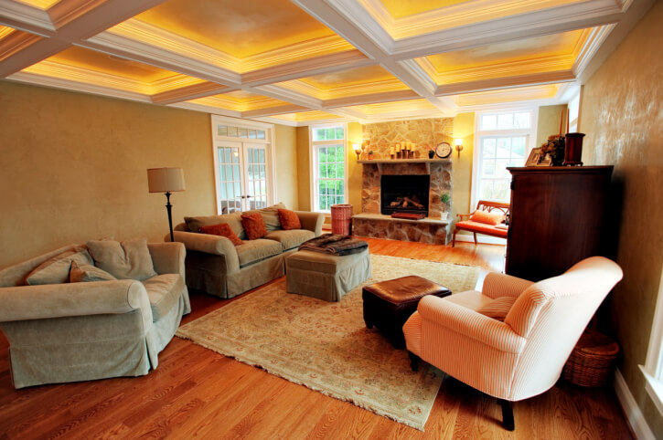 这个舒适，温暖色调的客厅设有丰富的硬木地板，石壁炉两侧的天花板高度的窗户，和室内照明的白色天花板梁细节。