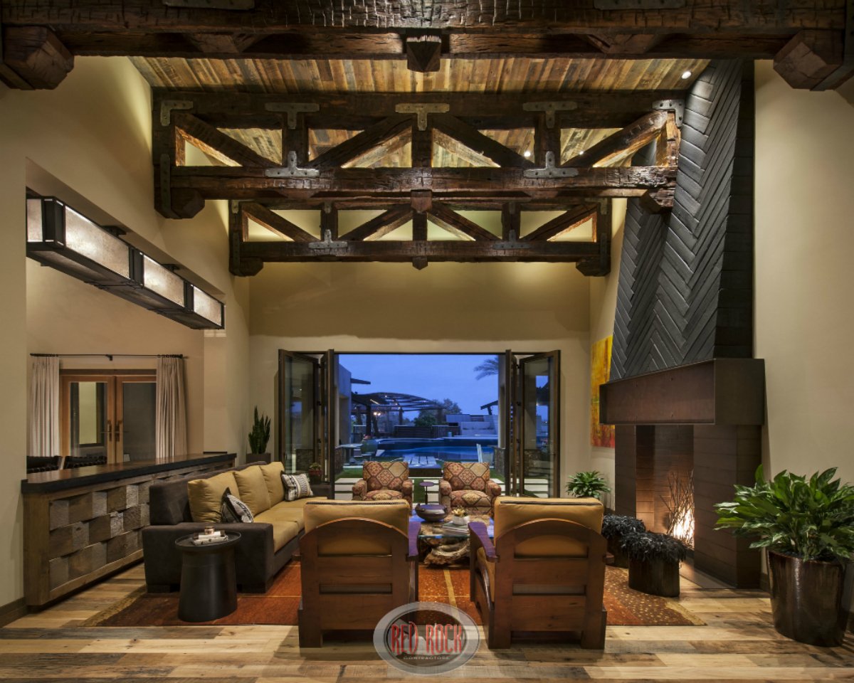 乡村风格的客厅，由红石承包商设计的高架、裸露的木梁天花板。