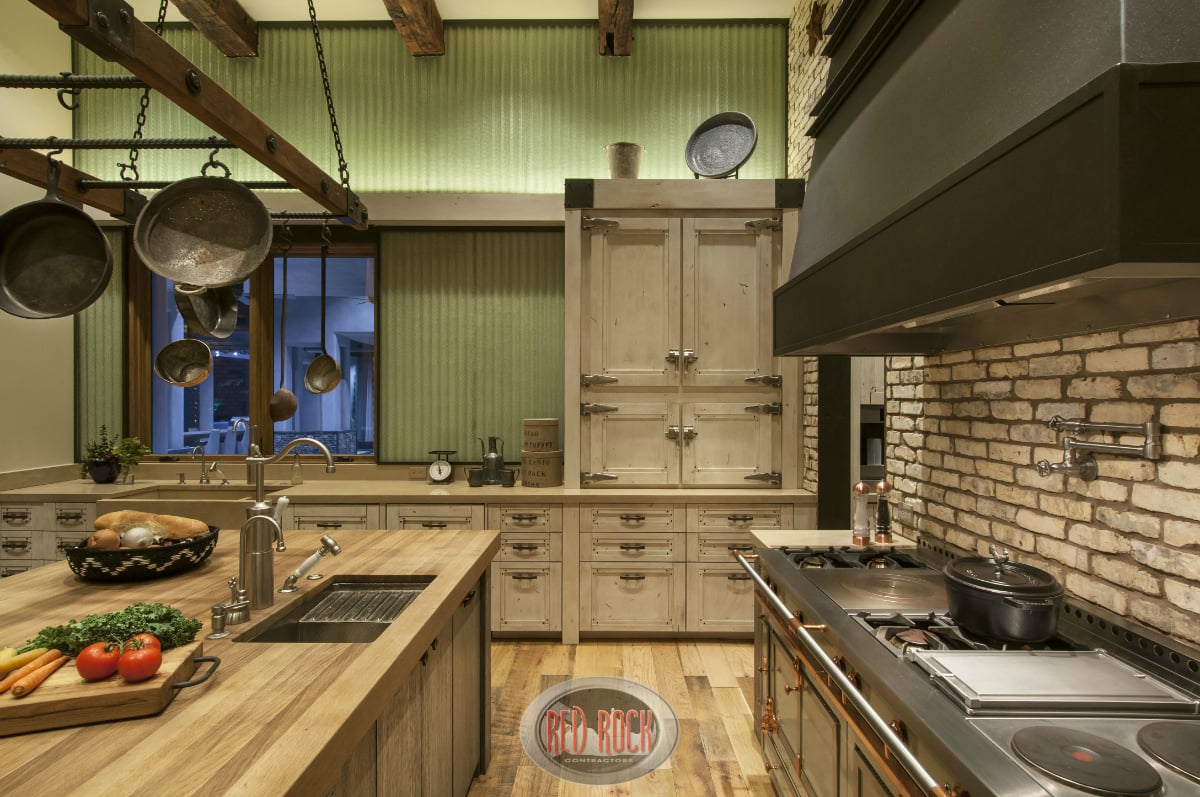 厨房的工作空间特写，包括大型厨师火炉，带水槽和砖后挡板的木顶岛。