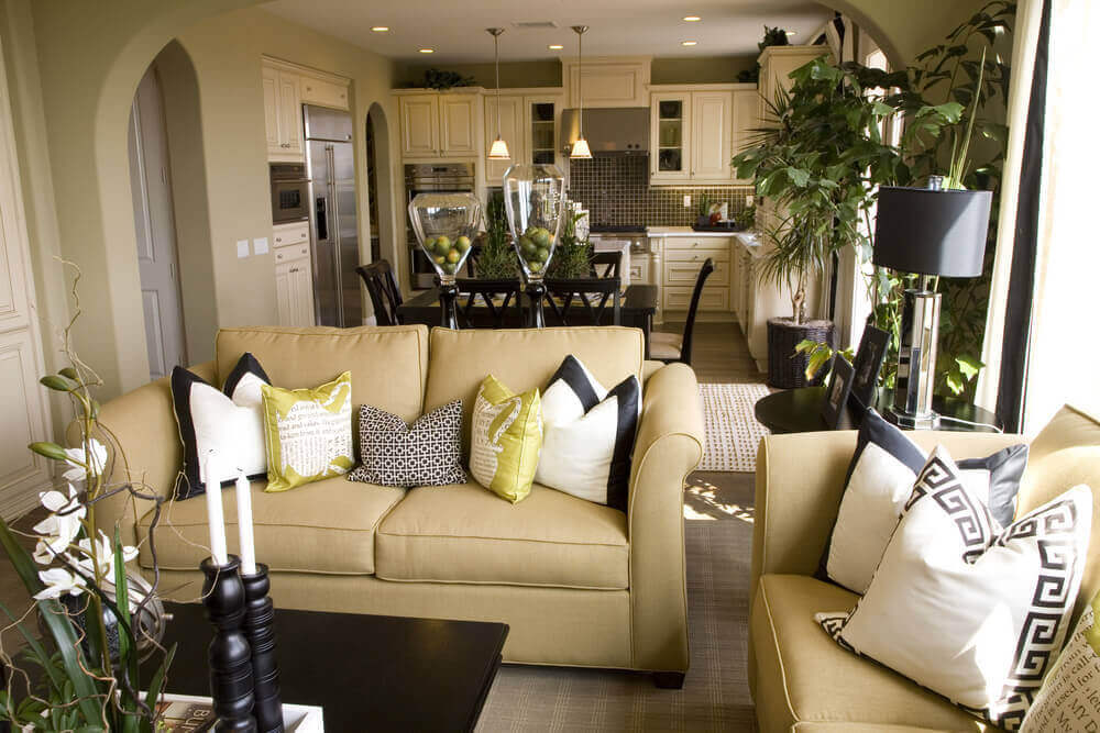 这间客厅以浅金色沙发、深色木咖啡桌和深色木餐厅为背景，与白色橱柜厨房共享空间。