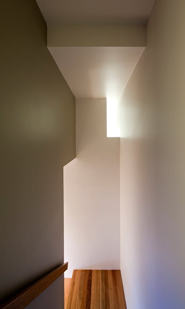 主楼梯延续了白色和天然木材的对比，巧妙的光线透过。
