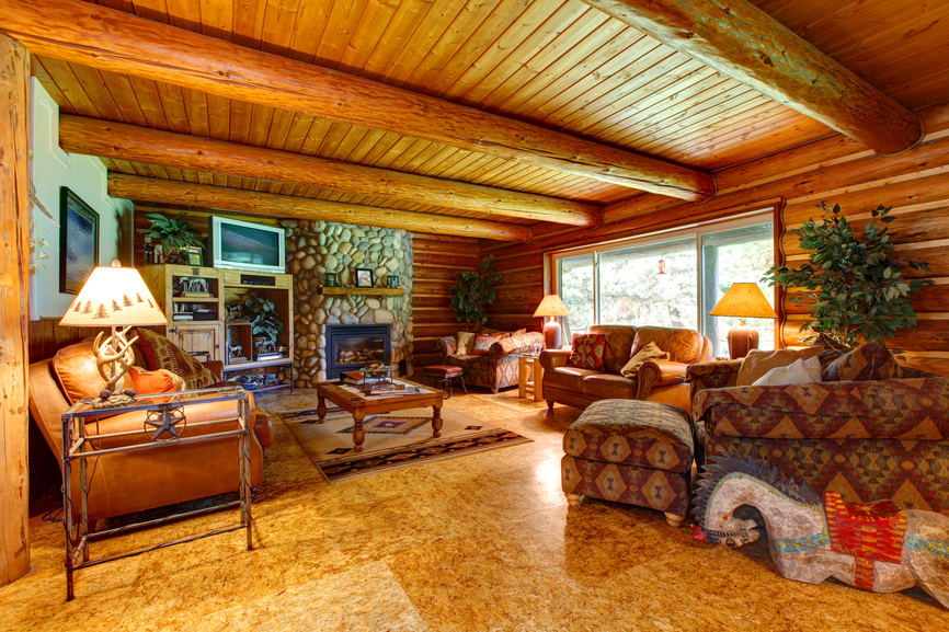 质朴风格的客厅充斥着天然原木设计，从墙壁到暴露的天花板横梁。大理石地板在一个匹配的色调容纳西南图案的家具和皮革沙发。石质壁炉位于大木咖啡桌后面。