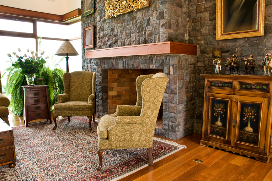 郁郁葱葱的纹理定义这个舒适的客厅。石质壁炉环绕至整面墙，上方有丰富的天然木质壁炉罩。天然硬木地板几乎与橱柜和配有抽屉的咖啡桌相匹配，而双高背椅则连接在中心的花纹地毯上。