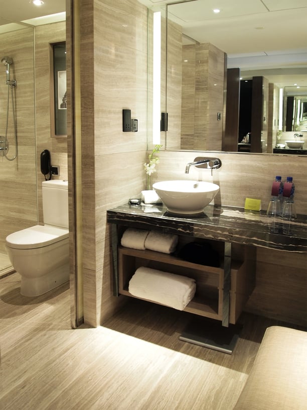 灰色大理石浴室设有静音的天然木质梳妆台存储在黑色大理石台面下，白色底座水槽。
