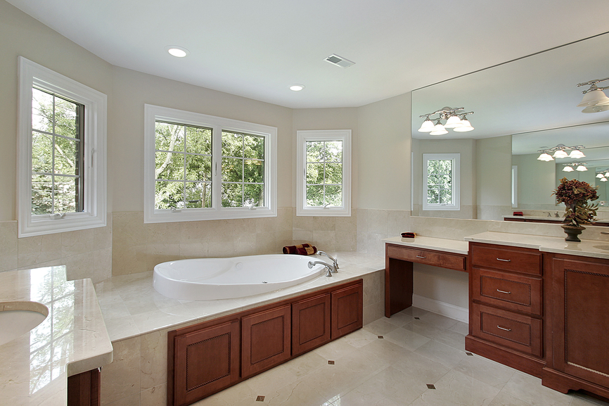 这是另一个u型浴室，樱桃木梳妆台橱柜和浴缸细节之间的强烈对比，浅色大理石地板和墙壁。