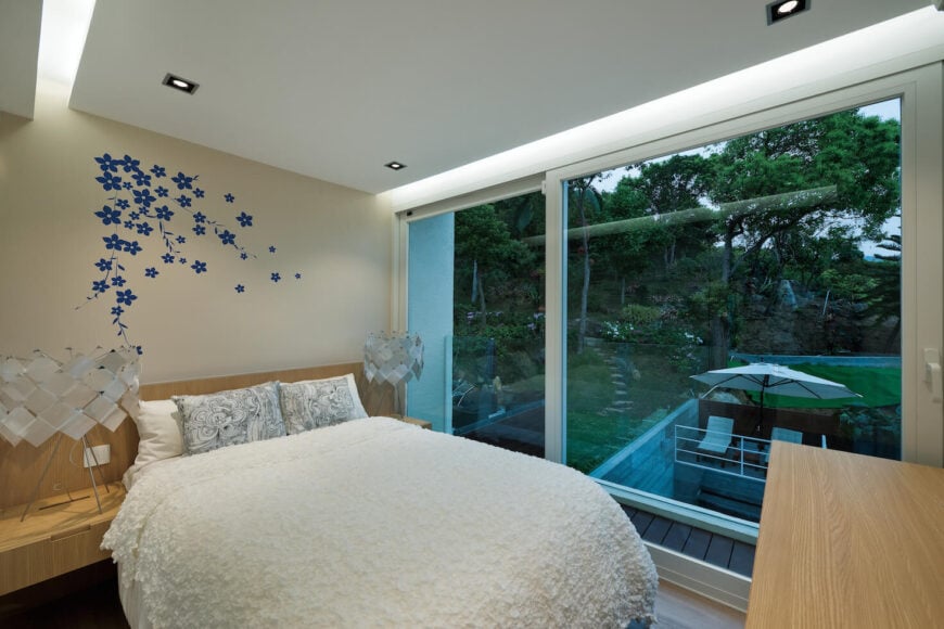 二楼卧室设有轻质天然木质搁架，嵌入天花板照明，巨大的滑动玻璃板通往阳台。