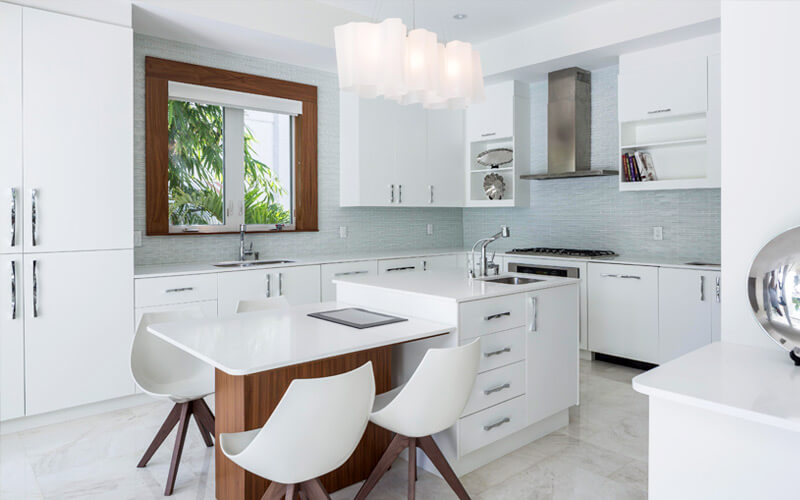 厨房具有彻底的现代约会，包括光滑的白色橱柜和台面，微型瓷砖蓝色后挡板，和两部分岛设有橱柜，内置水槽，和较低的用餐空间与天然木结构。
