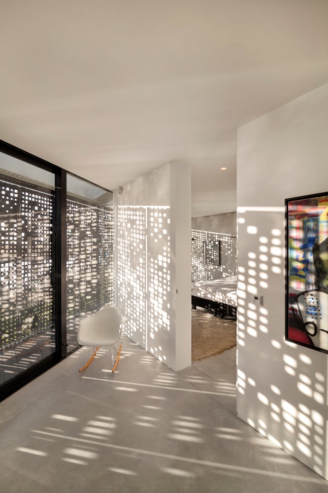 “代码”图案的百叶窗在整个住宅中提供了引人注目的斑驳阳光，就像上面走廊和卧室的视图所看到的那样。