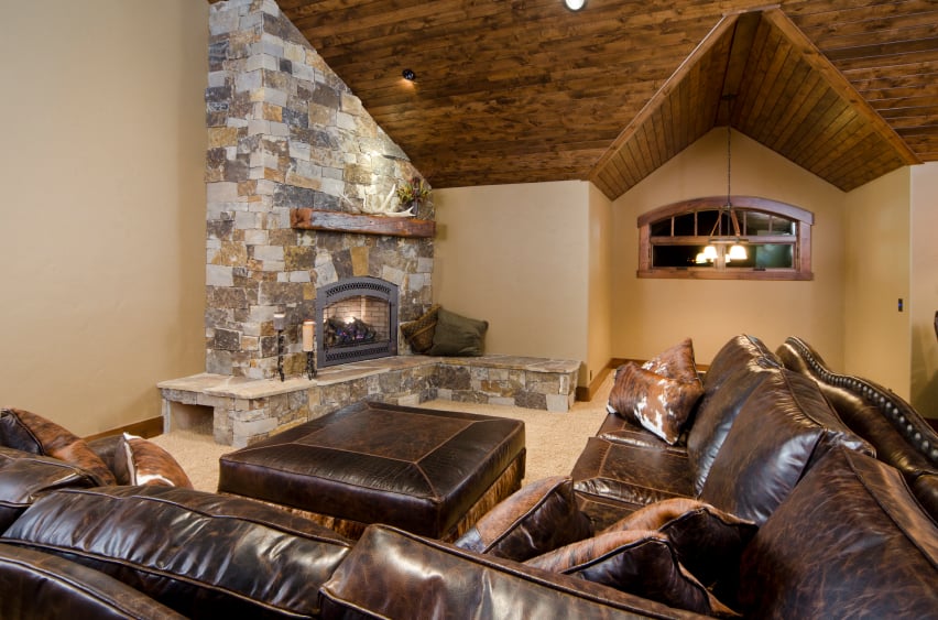 这间客厅以丰富的深色皮革家具为主，设有一个大型角石壁炉和拱形硬木天花板。